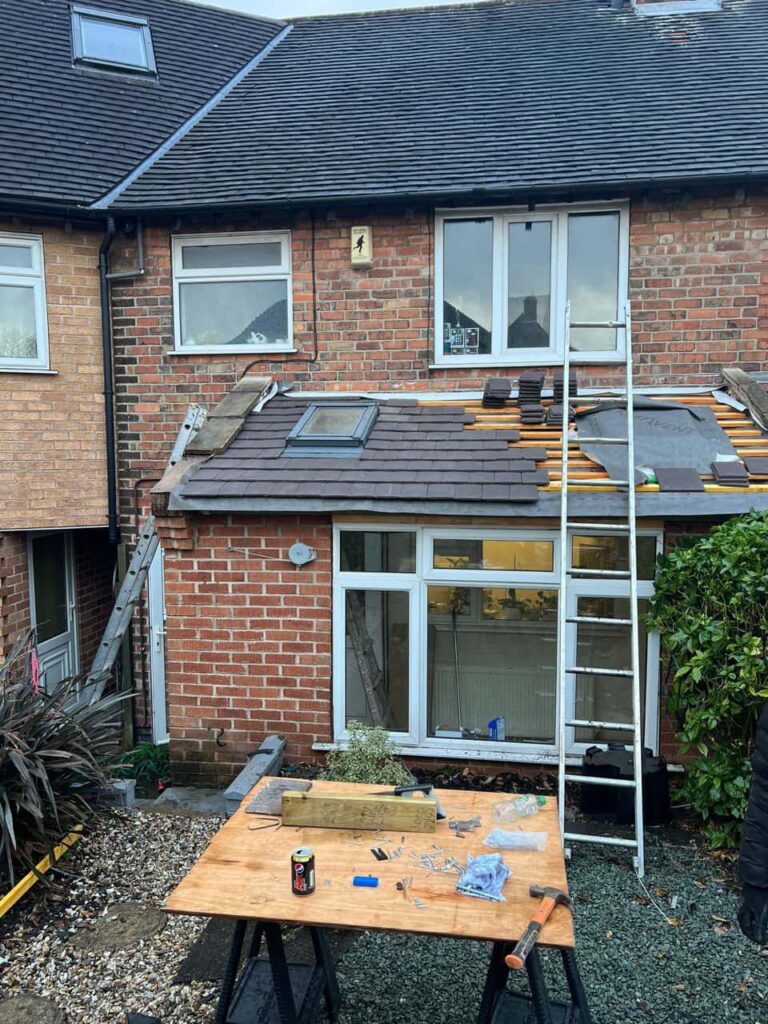 This is a photo of a roof extension that is having new roof tiles installed. This is a photo taken from the roof ridge looking down a tiled pitched roof on to a flat roof. Works carried out by MCM Roofing Repairs Lymington